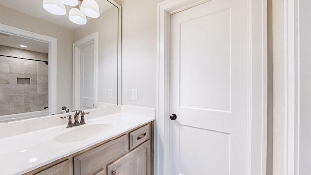 bathroom with a notable chandelier, vanity, and tiled shower / bath