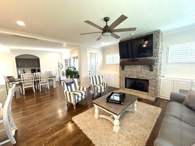 living room with ceiling fan, dark hardwood / wood-style flooring, a fireplace, and crown molding