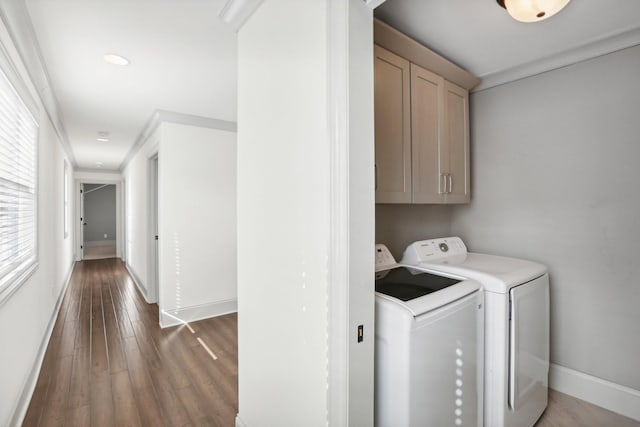 laundry area with dark wood-type flooring, ornamental molding, cabinets, and independent washer and dryer