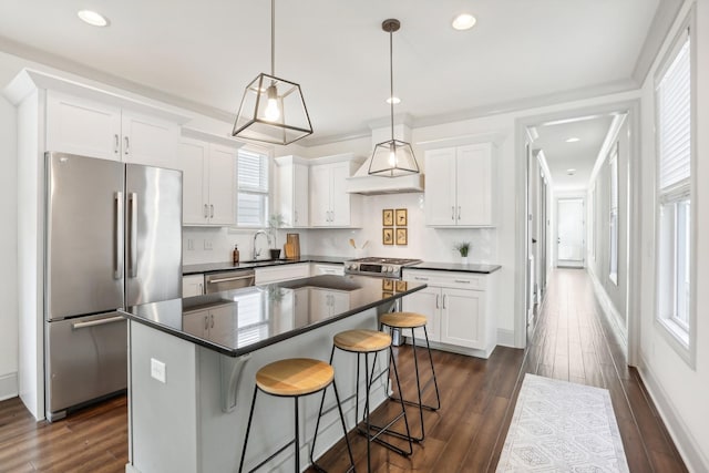 kitchen with appliances with stainless steel finishes, a center island, white cabinetry, and hanging light fixtures