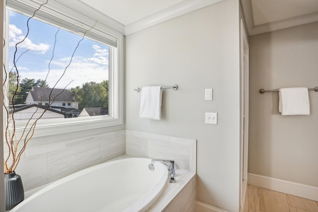 bathroom with crown molding and tiled bath