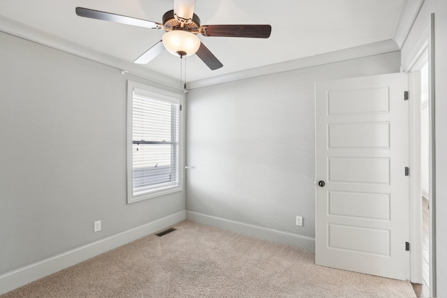 empty room featuring ceiling fan, ornamental molding, and light carpet