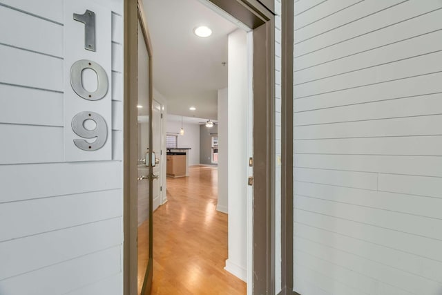 corridor with wood walls and light hardwood / wood-style flooring