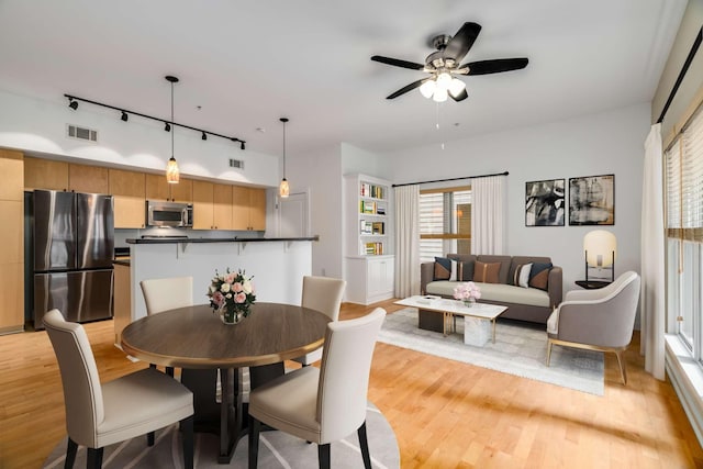 dining space featuring ceiling fan, rail lighting, and light hardwood / wood-style flooring