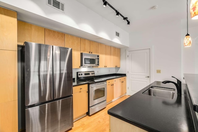 kitchen with sink, stainless steel appliances, light hardwood / wood-style floors, decorative light fixtures, and light brown cabinetry