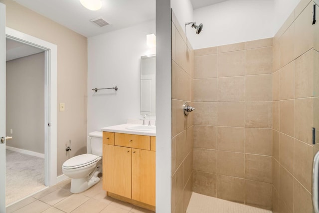 bathroom featuring a tile shower, tile patterned flooring, vanity, and toilet