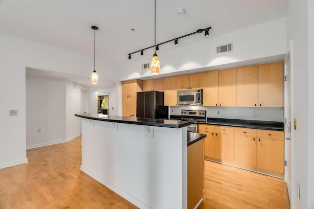 kitchen with pendant lighting, light brown cabinetry, stainless steel appliances, and light wood-type flooring