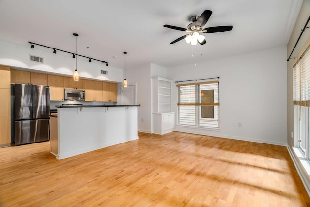 kitchen featuring track lighting, stainless steel appliances, ceiling fan, pendant lighting, and light hardwood / wood-style floors