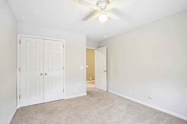 unfurnished bedroom with a closet, light colored carpet, and ceiling fan