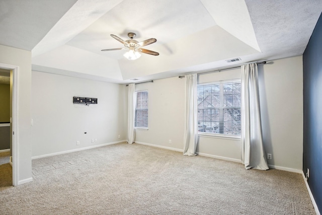 carpeted empty room featuring a raised ceiling, ceiling fan, and a textured ceiling