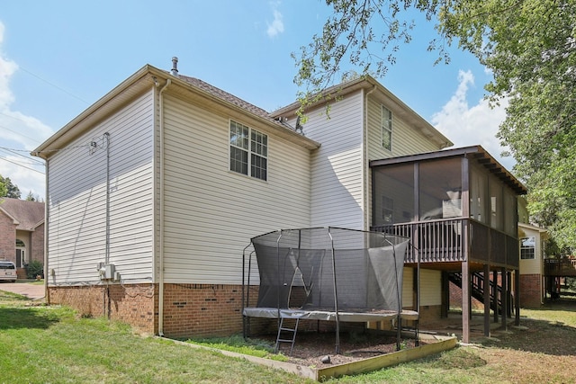 rear view of property with a yard and a trampoline