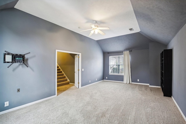 unfurnished living room with light carpet, a textured ceiling, ceiling fan, and lofted ceiling