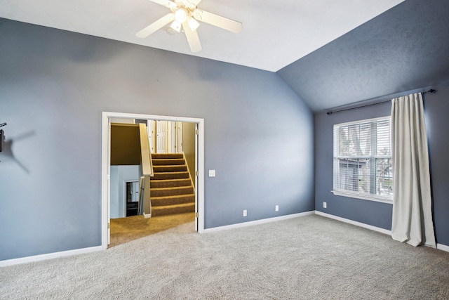 carpeted spare room featuring vaulted ceiling and ceiling fan