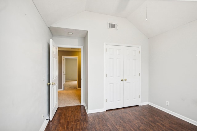 unfurnished bedroom featuring a closet, dark wood-type flooring, and vaulted ceiling