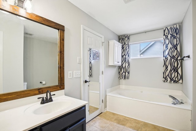 bathroom featuring a washtub, vanity, tile patterned floors, and toilet