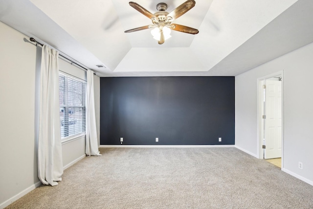 interior space featuring ceiling fan, a raised ceiling, and light carpet