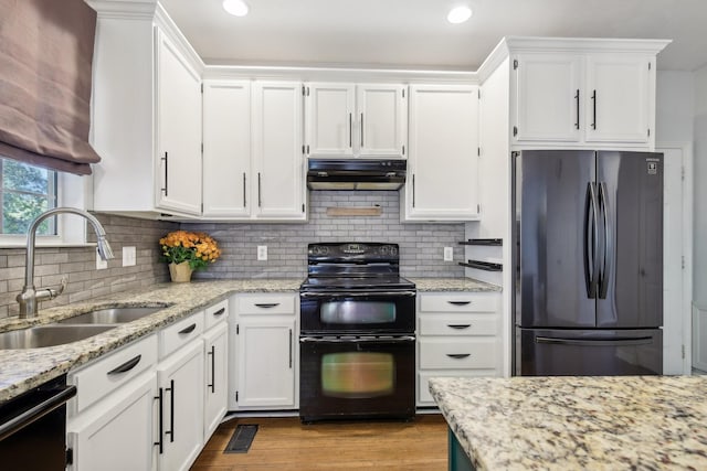 kitchen with sink, light stone counters, white cabinetry, and black appliances