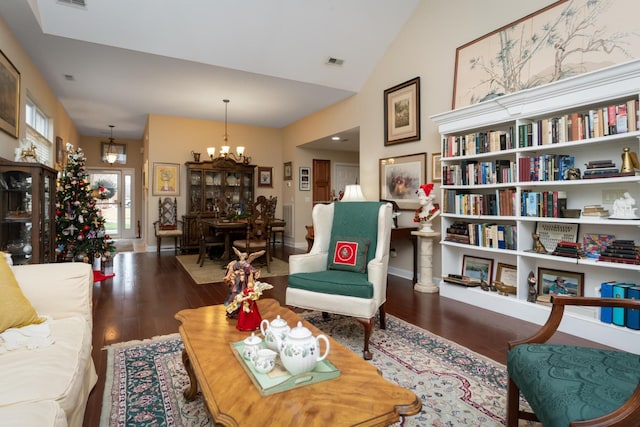 living room featuring dark hardwood / wood-style flooring, lofted ceiling, and a chandelier