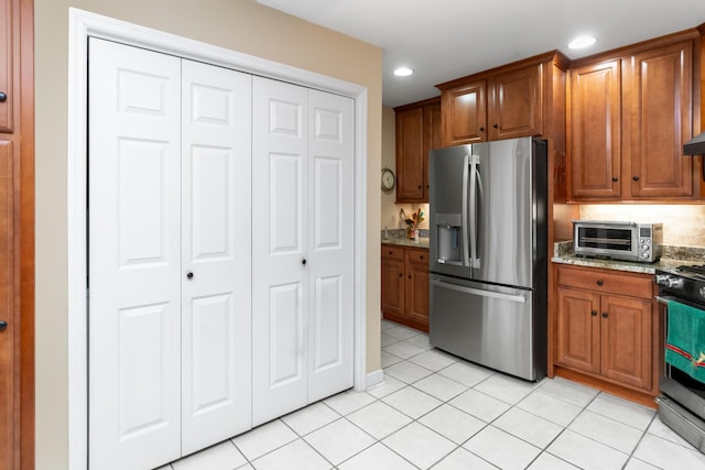 kitchen with light stone counters, light tile patterned flooring, and stainless steel appliances