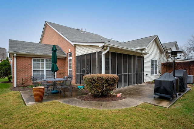 rear view of house with a lawn, a sunroom, and a patio