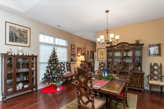 dining space with dark hardwood / wood-style floors and an inviting chandelier