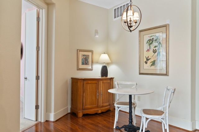 home office with dark wood-type flooring and a chandelier