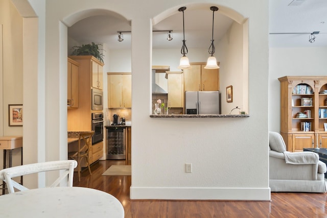 kitchen featuring wine cooler, wall chimney exhaust hood, light brown cabinets, pendant lighting, and stainless steel appliances