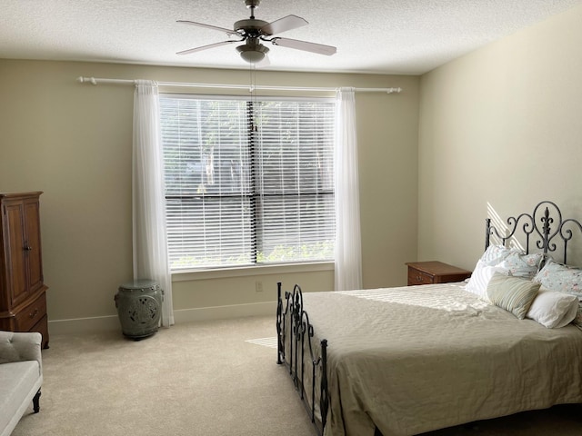 carpeted bedroom featuring ceiling fan and a textured ceiling