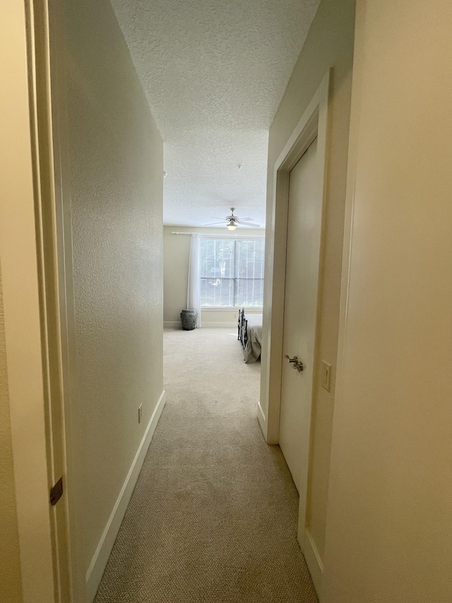 corridor featuring light carpet and a textured ceiling