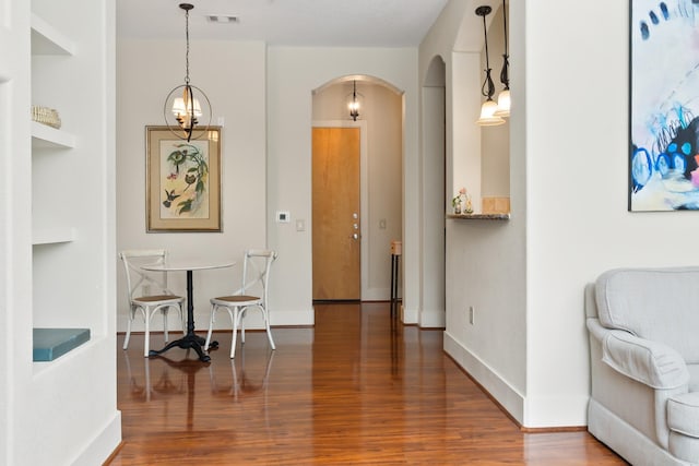 hallway with wood-type flooring and a chandelier