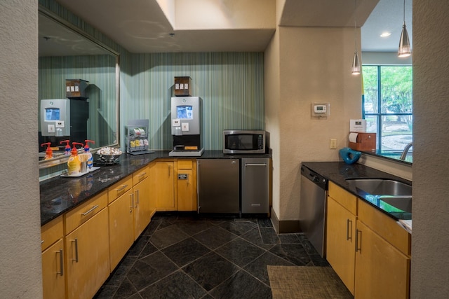 kitchen with appliances with stainless steel finishes, sink, pendant lighting, and light brown cabinets