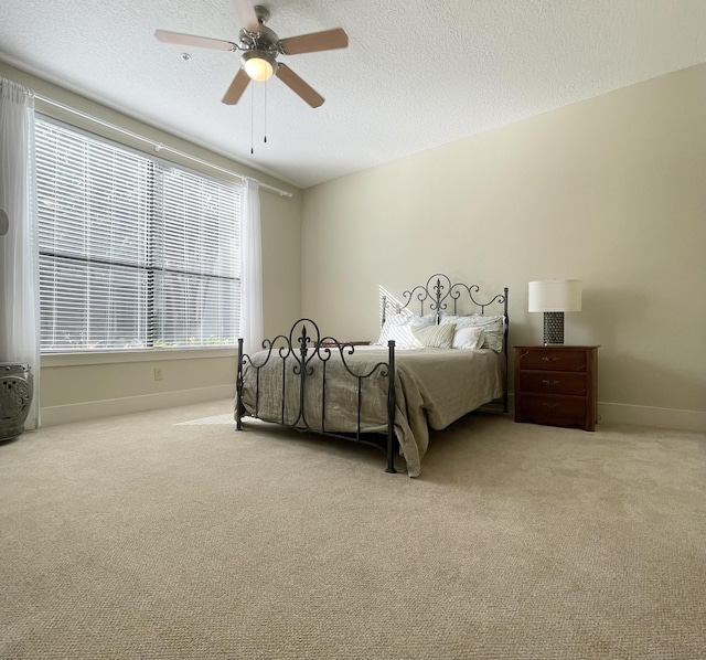 carpeted bedroom featuring ceiling fan and a textured ceiling