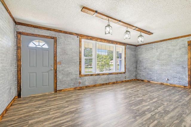 foyer entrance with a wealth of natural light, brick wall, and a textured ceiling