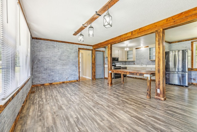 kitchen with brick wall, stainless steel appliances, sink, hardwood / wood-style floors, and hanging light fixtures