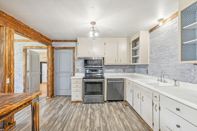 kitchen featuring stainless steel appliances, sink, light hardwood / wood-style flooring, white cabinetry, and hanging light fixtures