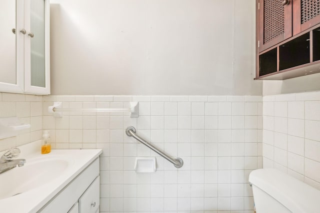 bathroom with vanity, toilet, and tile walls