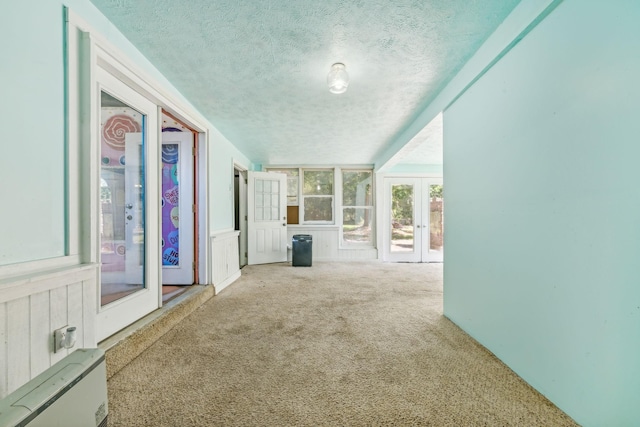 interior space with a textured ceiling, light carpet, and french doors