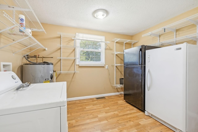 laundry area with electric water heater, light wood-type flooring, a textured ceiling, and washer / dryer