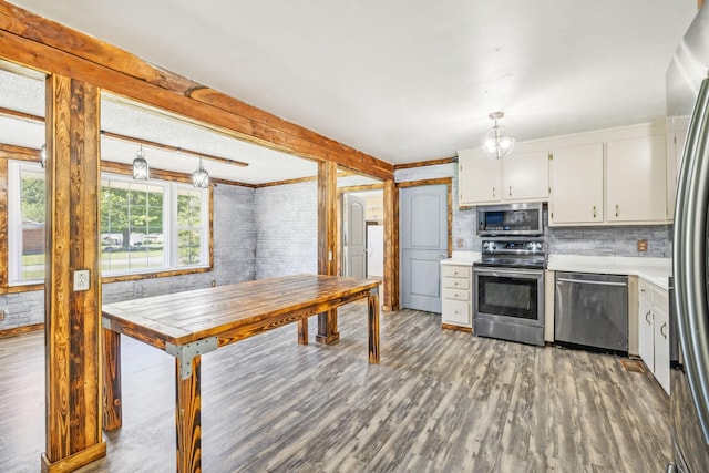 kitchen featuring backsplash, white cabinets, decorative light fixtures, and appliances with stainless steel finishes