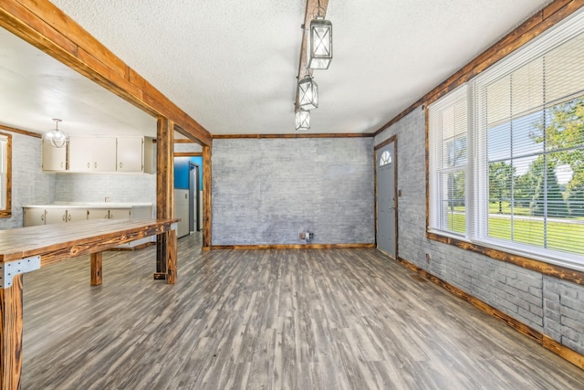 interior space featuring a textured ceiling, hardwood / wood-style flooring, and brick wall