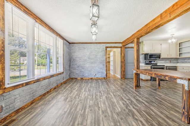 kitchen featuring stainless steel appliances, decorative backsplash, hanging light fixtures, and brick wall