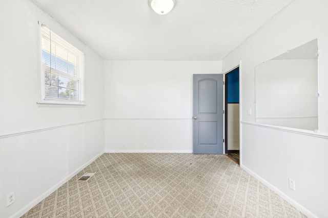 unfurnished room with a textured ceiling and light colored carpet