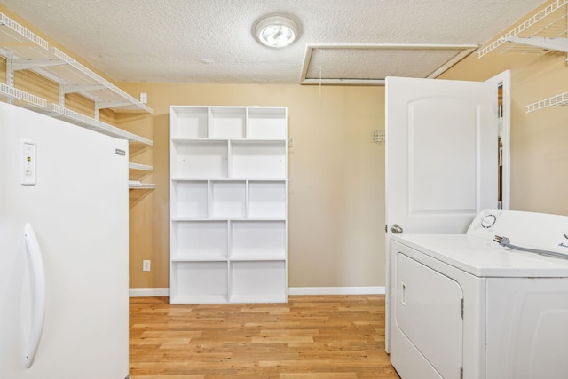 washroom featuring a textured ceiling, washer / clothes dryer, and light hardwood / wood-style flooring