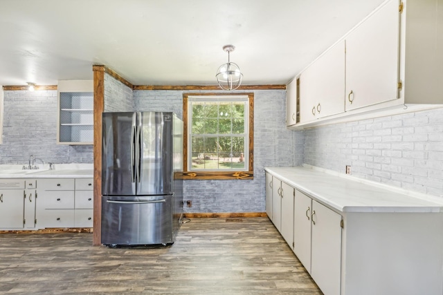 kitchen with stainless steel fridge, white cabinetry, pendant lighting, and sink