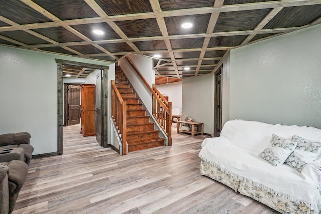 living room with light hardwood / wood-style floors and coffered ceiling