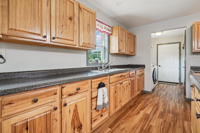 kitchen with sink, wood-type flooring, light brown cabinets, and washer / dryer