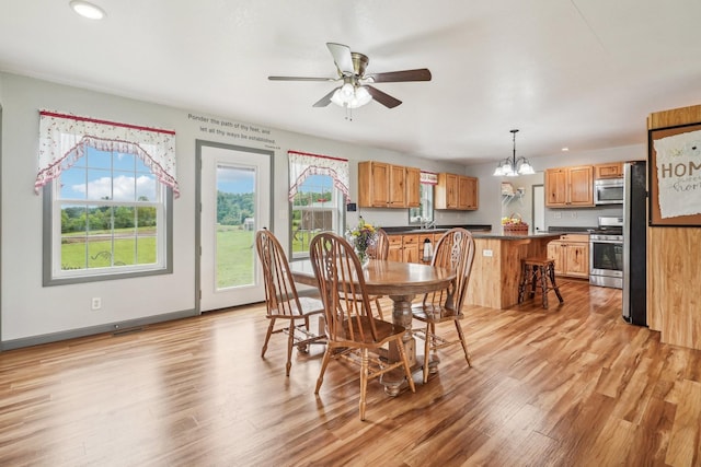 dining space with plenty of natural light, light hardwood / wood-style floors, ceiling fan with notable chandelier, and sink