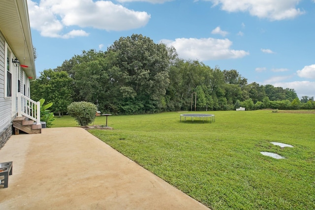 view of yard with a trampoline and a patio