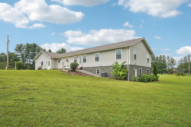 rear view of property with cooling unit and a lawn