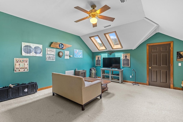 carpeted living room with ceiling fan and vaulted ceiling with skylight